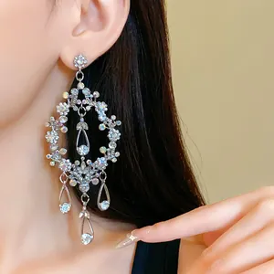 Close-up detail of oversized rhinestone hollow teardrop tassel earrings worn by model
