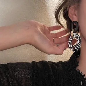Primer plano de pendientes vintage de acrílico con estampado de cebra y eslabones.