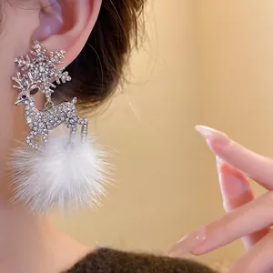 Close-up of elegant Christmas deer earrings with rhinestones and white fur pom-poms