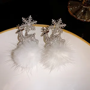 Detailed view of rhinestone reindeer earrings with white pom-poms and snowflake charms