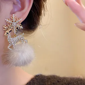 Close-up of snowflake and deer earrings with sparkling rhinestones and soft fur ball.