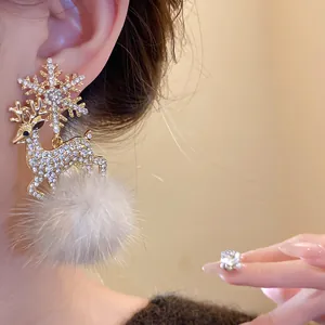 Close-up of rhinestone reindeer earrings with a grey fur pompom and snowflake stud