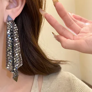 Macro detail view of vintage silver triangle sequin tassel earrings worn by a model