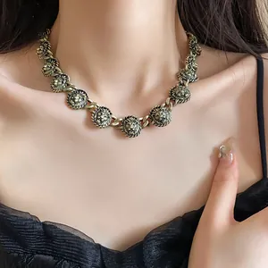 Dettaglio di una collana vintage con teste di leone in bronzo su una modella donna