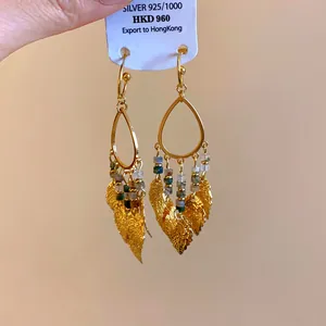 Detail shot of Bohemian leaf tassel earrings with colorful beads and gold finish.