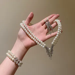 Detailed view of elegant double-layer pearl necklace, bracelet and earring set on hand