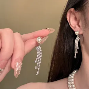 Detailed view of elegant pearl drop earrings with crystal tassels and a pearl necklace