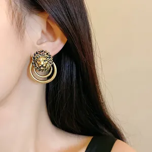 Dettaglio ravvicinato di orecchini vintage placcati in oro a testa di leone su modella