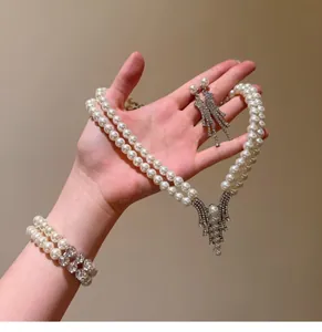 Detailed macro view of an elegant double-layer pearl jewelry set presented in hand