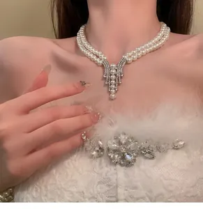 Detailed view of elegant double-layered pearl necklace with crystal pendant on model.