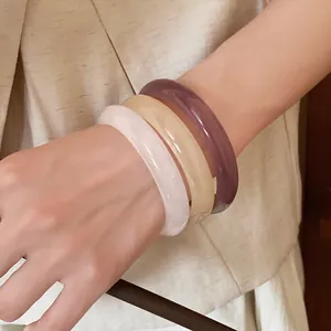 Stylish set of three colorful resin bangles in white, cream, and purple on a wrist