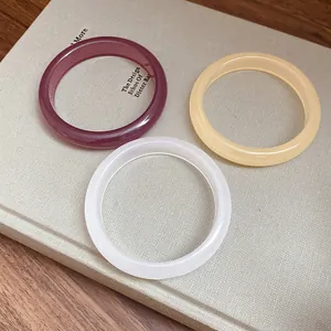 Close-up of minimalist resin bangles in burgundy, beige and frosted white colors.