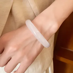 Elegant white resin bangle with a round profile, shown in a close-up detail on wrist