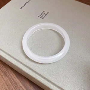 Detail view of a translucent white resin bangle resting on a minimalist design book