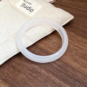 Detail of a translucent white resin bangle with a smooth finish on a wooden table