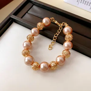 Détail d'un élégant bracelet en perles pêche avec des billes géométriques dorées