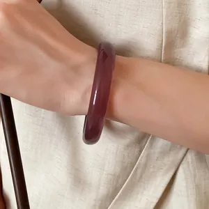 Detail shot of a deep purple translucent resin bangle on a wrist, new Chinese style.