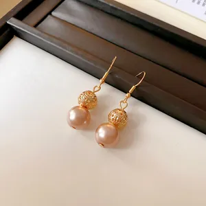 Gros plan de boucles d'oreilles rétro français avec perles dorées et perles roses