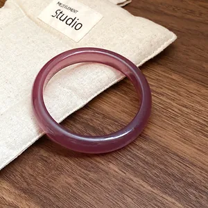 Detailed macro shot of a translucent purple resin bangle on a rustic wooden surface
