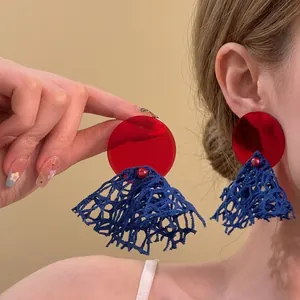 Vista detallada de pendientes con borlas rojas y azules para un look de playa verano