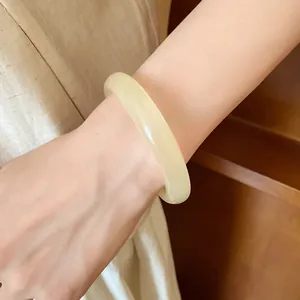 Detail close-up of a minimalist cream-colored resin bangle worn on a woman's wrist.