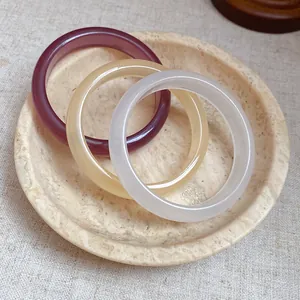 Detail view of a set of three colorful resin bangles in a stone decorative bowl