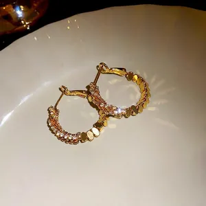 Elegant gold plated hoop earrings with shimmering cubic zirconia stones on plate