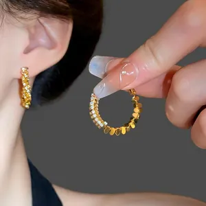 Elegant gold hoop earrings with sparkling zircon stones and polished gold disc details