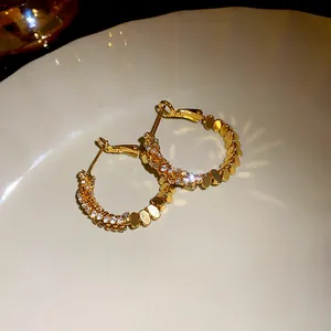 Detailed macro view of gold hoop earrings with sparkling zircon stones on plate
