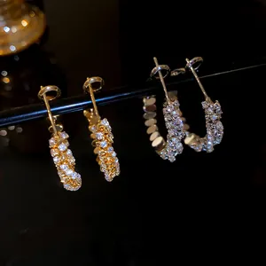 Macro view showing the sparkling zircon inlay of gold and silver hoop earrings
