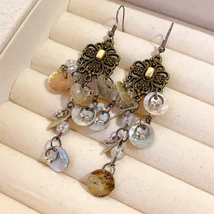 Close-up of bohemian floral drop earrings with iridescent shell tassels in vintage box