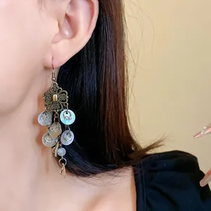 Close-up of Bohemian vintage long tassel earring with flower filigree and shell discs