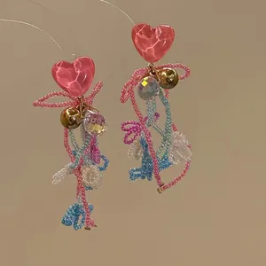 Detailansicht der handgefertigten rosa Herzharz-Ohrringe mit bunten Perlenquasten und Kristall.