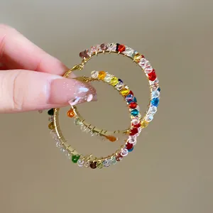 Nahaufnahme von farbenfrohen Regenbogen-Perlenohrringen mit feinem Golddraht-Wickeldetail