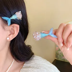 Detailansicht einer Meerjungfrauenschwanz-Haarspange mit glitzernden Perlen im Haar.