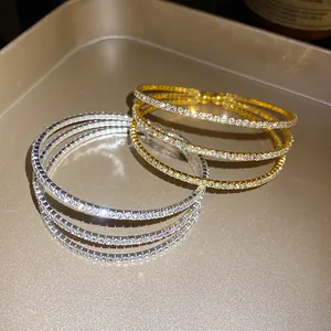 Detailed view of gold and silver three-layer rhinestone open bangles on a tray