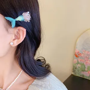 Nahaufnahme einer Meerjungfrauenschwanz-Haarspange und Perlenohrrings an einem Model