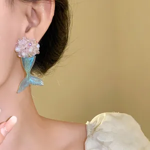 Nahaufnahme eleganter Meerjungfrauenschwanz-Ohrringe mit blauem Anhänger