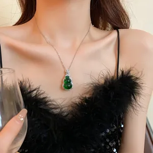 Detail view of a Chinese-style green resin gourd pendant necklace on a model.