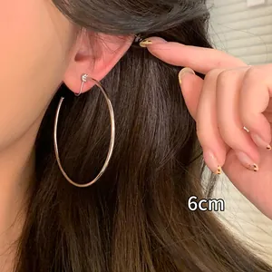 Close-up of a 6cm large silver hoop earring worn to show its size and style.