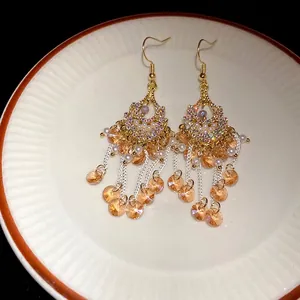 Elegant Bohemian tassel earrings with amber glass beads and pearls on white plate