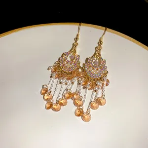 Close-up of Bohemian rhinestone and pearl tassel earrings on white plate