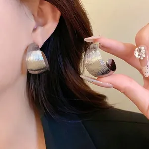 Orecchini geometrici a C in argento con strisce testurizzate verticali indossati da modella