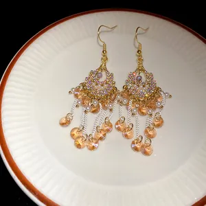 Detail of bohemian tassel earrings with rhinestones, pearls and orange glass beads