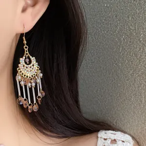 Close-up view of bohemian gold-tone tassel hook earrings with rhinestones and pearls