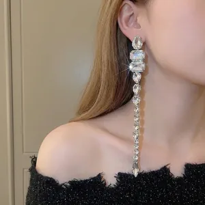 Eleganti orecchini lunghi con nappe e strass trasparenti scintillanti sul modello.
