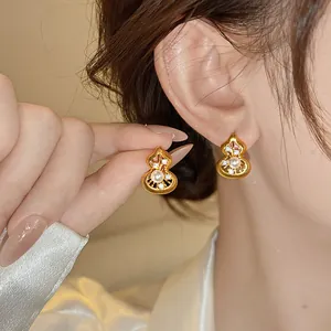 Nahaufnahme von eleganten goldenen Flaschenkürbis-Ohrringen mit Perlen und Zirkonia-Details