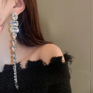 Primo piano di eleganti orecchini lunghi a nappa con strass scintillanti su una modella.