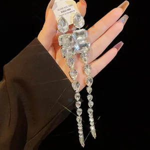 Dettaglio di orecchini lunghi a nappa con strass scintillanti a goccia d'acqua.