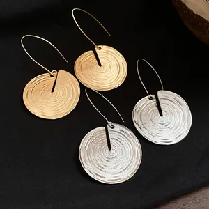 Detailansicht gold- und silberfarbener runder Ohrringe mit spiralförmiger Holzmaserung